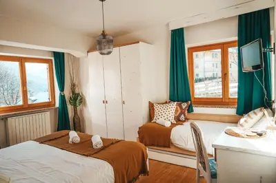 two beds in a room with green curtains at Casa di Franz in Vigo di Fassa