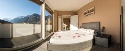 a bedroom with a bed and a balcony with a view at Dolce Vista in Merano