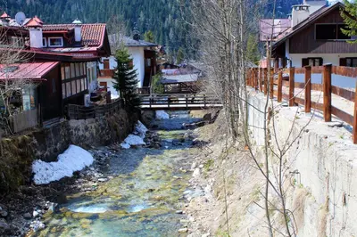 a river in a town with a bridge and buildings at Chalet Margoni in Canazei