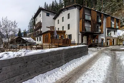 a building in the snow next to a road at Chalet Margoni in Canazei