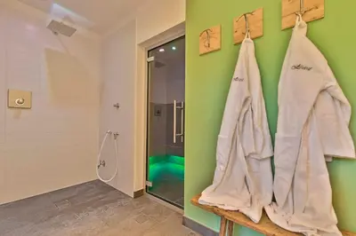 a bathroom with a shower and towels hanging on a wall at Hotel Steinrösl in San Cassiano