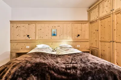 a bedroom with a large bed with wooden cabinets at Hotel Steinrösl in San Cassiano