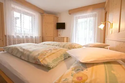 a bedroom with two beds and two windows at Hotel Steinrösl in San Cassiano