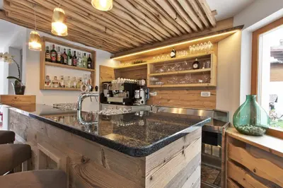 a kitchen with a bar with a coffee maker at Hotel Steinrösl in San Cassiano