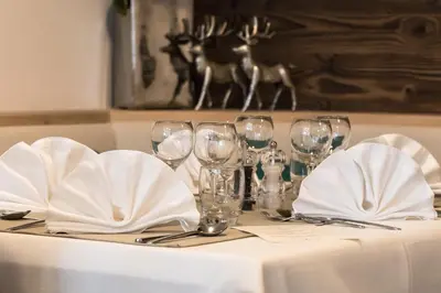 a table with wine glasses and napkins on it at Hotel Steinrösl in San Cassiano
