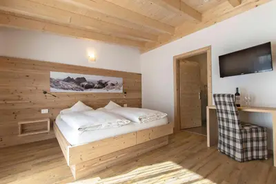 a bedroom with a bed with a wooden wall at Hotel Steinrösl in San Cassiano