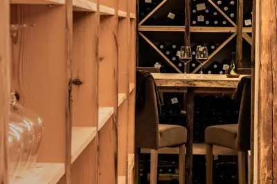 a wine cellar with two chairs and a table with wine bottles at Hotel Steinrösl in San Cassiano