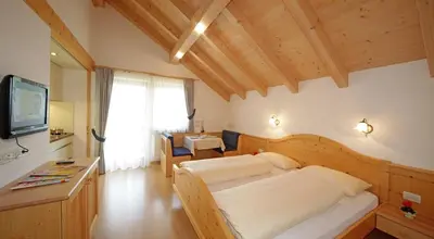 a bedroom with a large bed and a television at Apartments Lasteis in La Villa