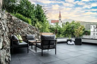 a patio with chairs and a table and a church at Apartment Schifta in Chienes