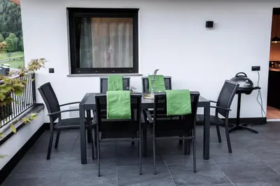 a black table and chairs with green napkins on it at Apartment Schifta in Chienes