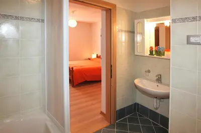 a bathroom with a sink and a shower and a bed at Casa Lisa in Falcade