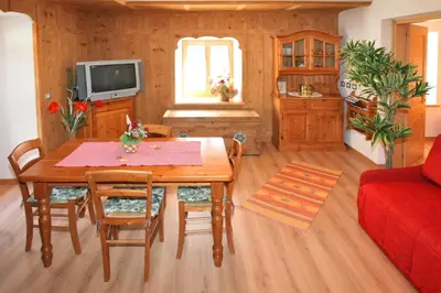 a living room with a table and a red couch at Casa Lisa in Falcade