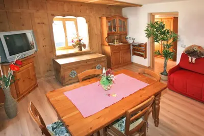 a living room with a wooden table and a red couch at Casa Lisa in Falcade