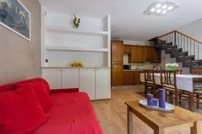 a living room with a red couch and a table at Casa NeveXenne & La Casa di Blek in Alleghe