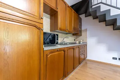 a kitchen with wooden cabinets and a sink at Casa NeveXenne & La Casa di Blek in Alleghe