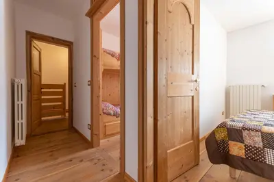 a room with a wooden door and a bedroom with a bed at Cesa al Monech in Selva di Cadore