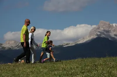 a family walking on a hill with mountains in the background at Cesa al Monech in Selva di Cadore