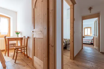 a room with a wooden door and a table with a chair at Cesa al Monech in Selva di Cadore