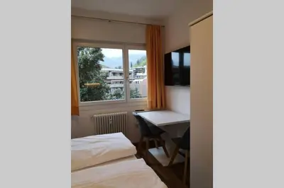 a room with two beds and a desk and a window at Appartment Barbara in Bolzano