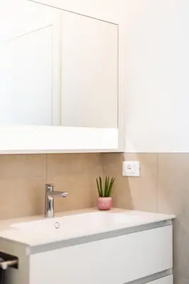 a bathroom sink with a white cabinet and a plant at CityPointApartments- Theatre in Merano