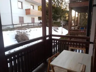 a balcony with a table and a snow covered yard at Siusi Sciliar Apartment in Siusi