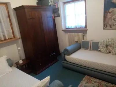 a bedroom with a bed and a couch and a window at Siusi Sciliar Apartment in Siusi