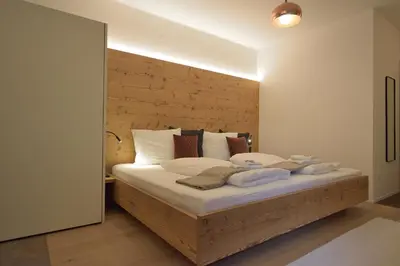 a bedroom with a large bed with a wooden headboard at CityChalet romantic Bozen in Bolzano