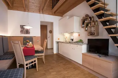 a kitchen and dining room with a dining table and a kitchen with white cabinets at Callhof - Bio Obsthof in Lana