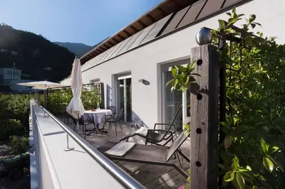 a balcony of a house with a table and chairs at Callhof - Bio Obsthof in Lana