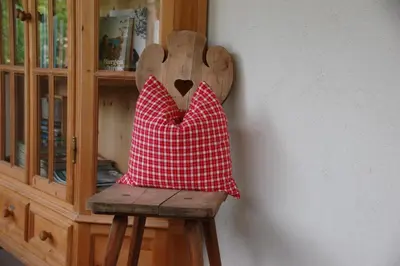 a red and white pillow sitting on a wooden chair at Callhof - Bio Obsthof in Lana