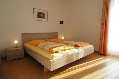 a bedroom with a bed with a wooden headboard at Ferienwohnungen Luggin in Caldaro