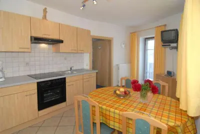 a kitchen with a table with a yellow and orange table cloth at Ferienwohnungen Luggin in Caldaro