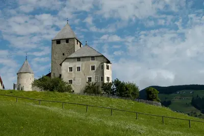 an old castle on top of a green hill at L'GROF - AL CONTE in San Martino in Badia