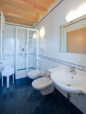 a white bathroom with two sinks and a shower at L'GROF - AL CONTE in San Martino in Badia