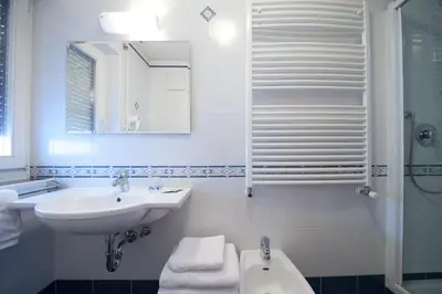 a white bathroom with a sink and a shower at L'GROF - AL CONTE in San Martino in Badia