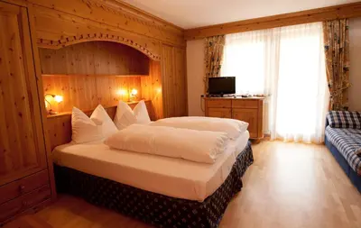 a bedroom with a large bed and a blue couch at L'GROF - AL CONTE in San Martino in Badia