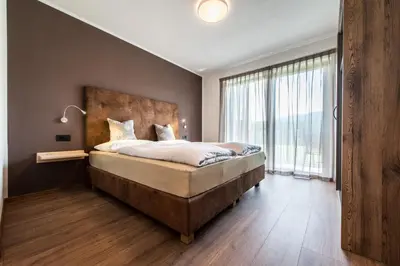 a bedroom with a large bed and a large window at Chalet Kristall - Dolomites Garden Chalet in Falzes