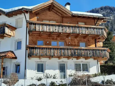a large wooden house with a deck on it at Luxury Apartment Daema in Selva di Val Gardena