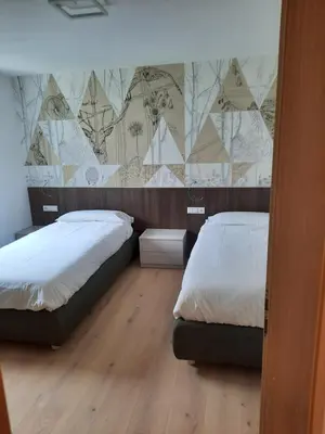 a bedroom with two beds and a mural on the wall at Luxury Apartment Daema in Selva di Val Gardena