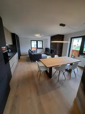 a kitchen and living room with a wooden table and chairs at Luxury Apartment Daema in Selva di Val Gardena