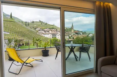a room with a balcony with a table and chairs at Zilli Studio Apartments in Termeno