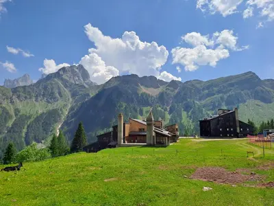 a bedroom with a bed and a table and a window at Valles Vacanze - ski in & ski out in Falcade