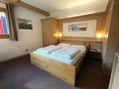 a bedroom with a bed and a table and a kitchen at Valles Vacanze - ski in & ski out in Falcade