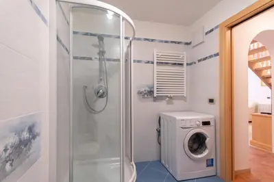 a bathroom with a shower and a washing machine at Chalet Butterfly 1 in Mazzin
