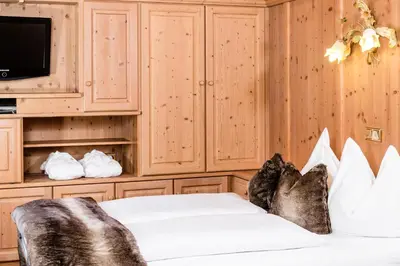 a bedroom with a bed and a tv and cabinets at Apartments Hotel Garden in Selva di Val Gardena