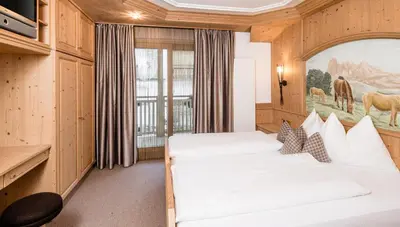 a bedroom with two beds and a painting on the wall at Apartments Villa Gardena - Gardenahotels in Selva di Val Gardena