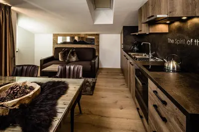 a kitchen with a table and a couch in a room at Apartments Villa Gardena - Gardenahotels in Selva di Val Gardena
