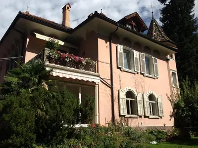 a pink house with a balcony with flowers on it at Apartments Villa Anita in Bolzano
