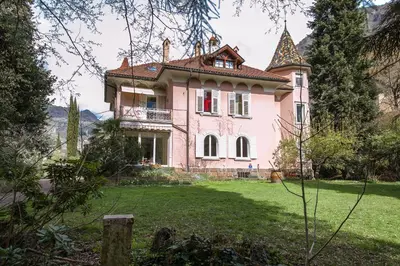 a large pink house on a green yard at Apartments Villa Anita in Bolzano