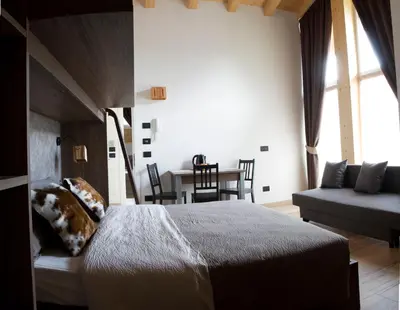 a bedroom with a bed and a table and chairs at Alpenrooms in Transacqua